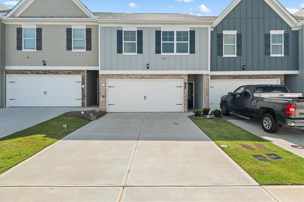 Multi unit property featuring a garage, board and batten siding, brick siding, and driveway