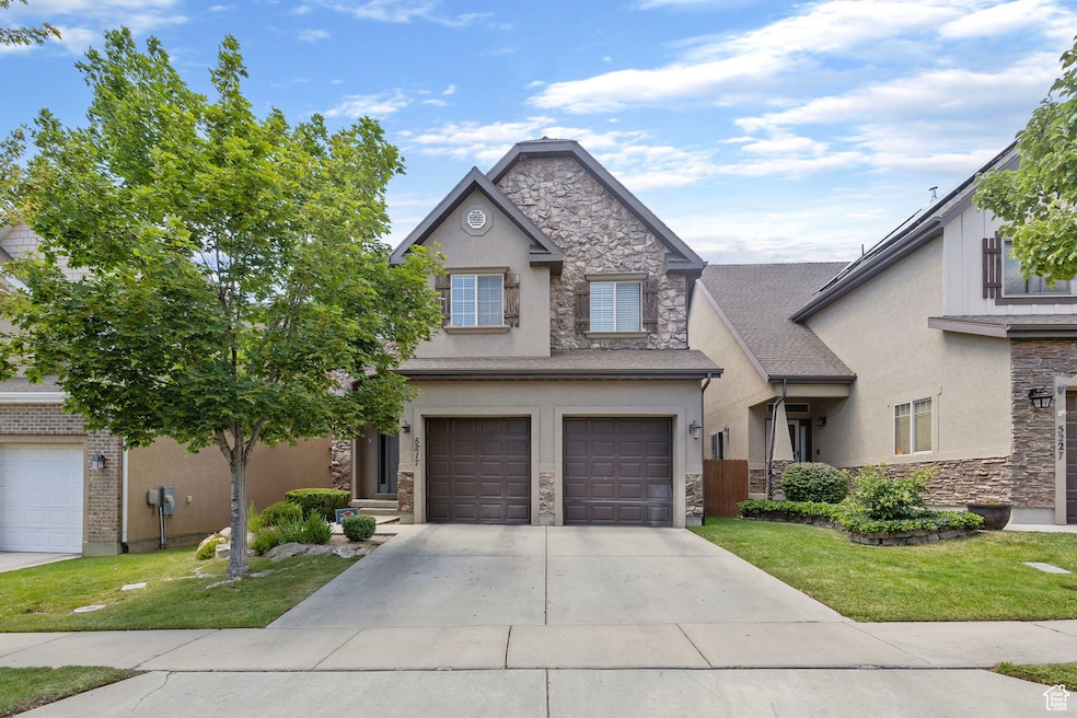 Traditional-style home featuring stone siding, driveway, a garage, and stucco siding