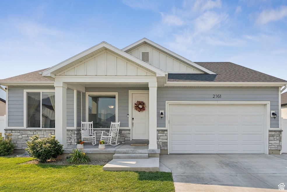 View of front of property with stone siding, a porch, a shingled roof, and board and batten siding