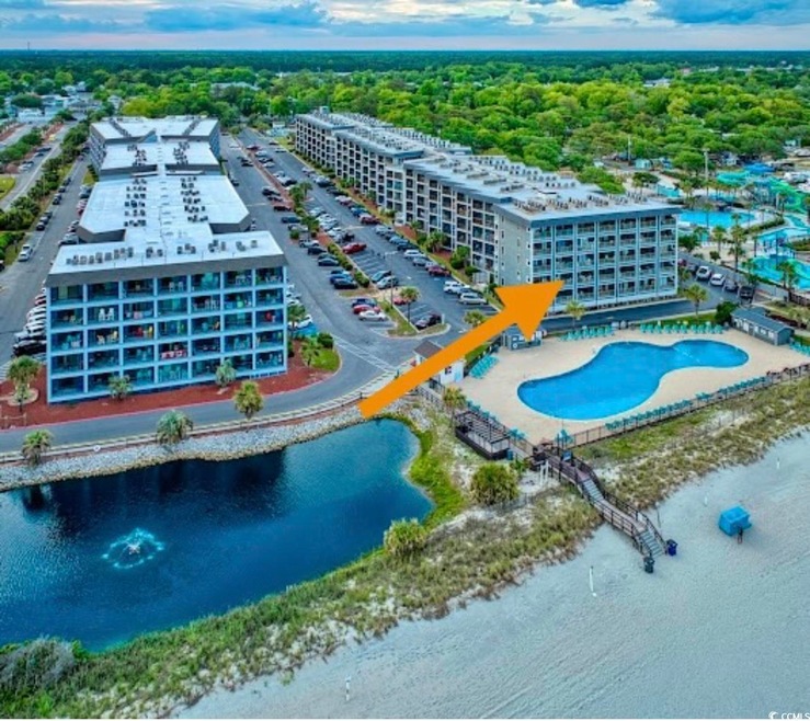 Aerial view of a pool, apartment complex / building, and a large body of water