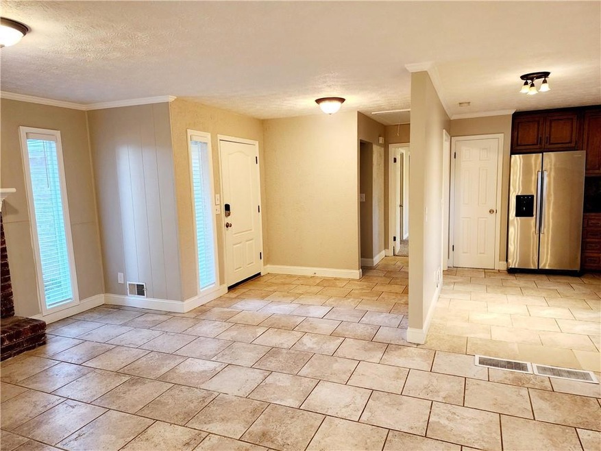 Tiled entryway with plenty of natural light, a brick fireplace, ornamental molding, and a textured ceiling