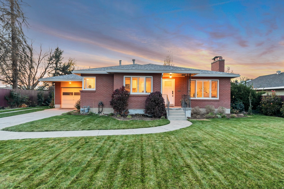 View of front of home featuring brick siding, concrete driveway, a chimney, an attached garage, and covered porch
