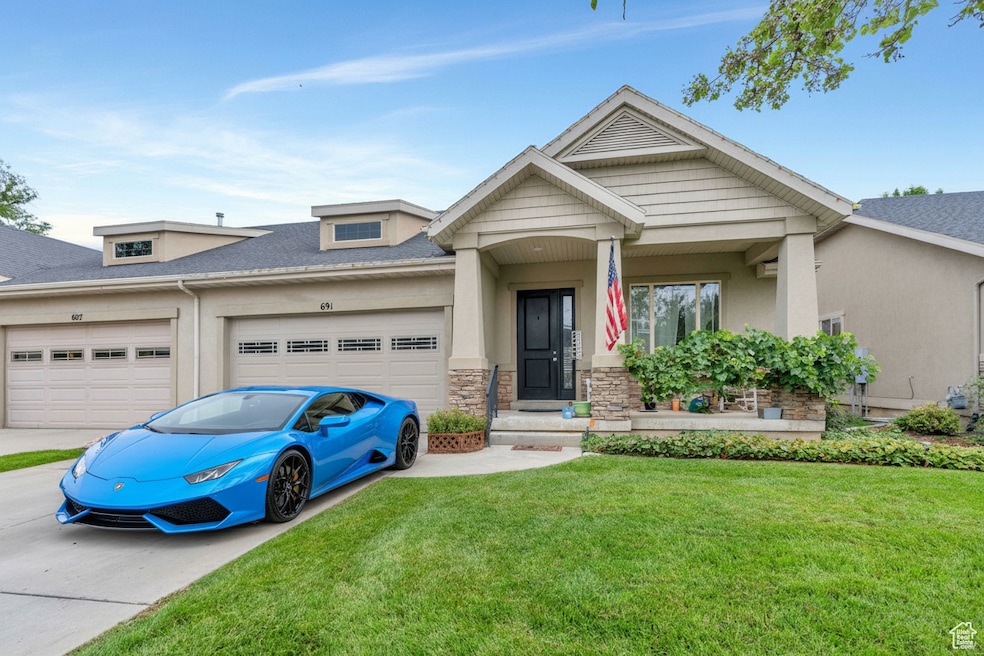 South facing front of the home featuring stucco siding, a front yard, concrete driveway, stone siding, and a shingled roof (car is virtual)