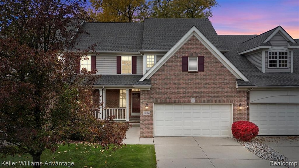 Traditional home featuring roof with shingles, covered porch, driveway, a garage, and brick siding