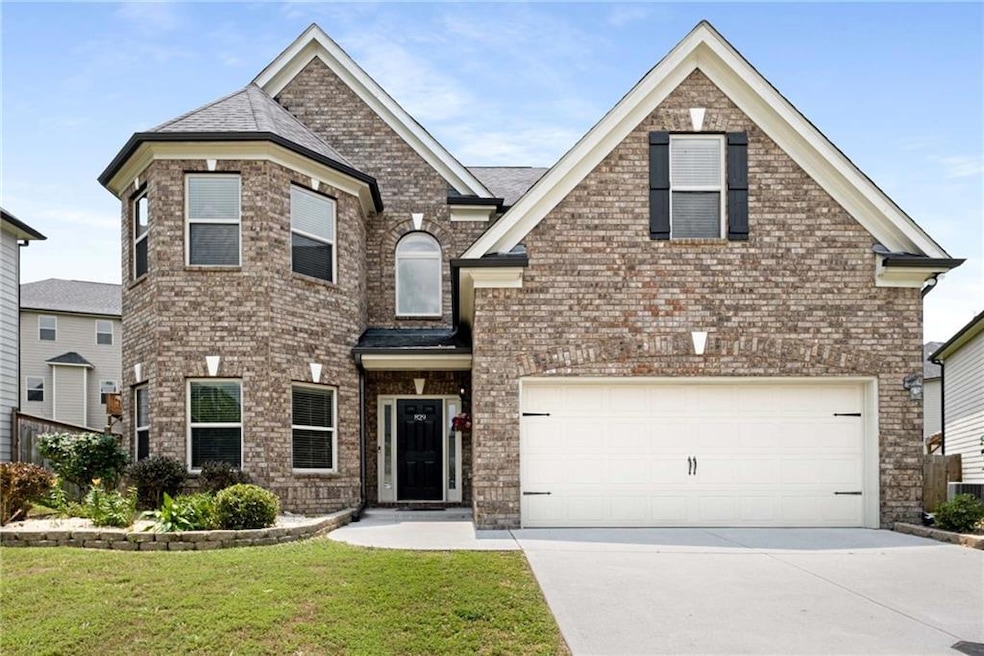 View of front facade with driveway, a front yard, a garage, and brick siding