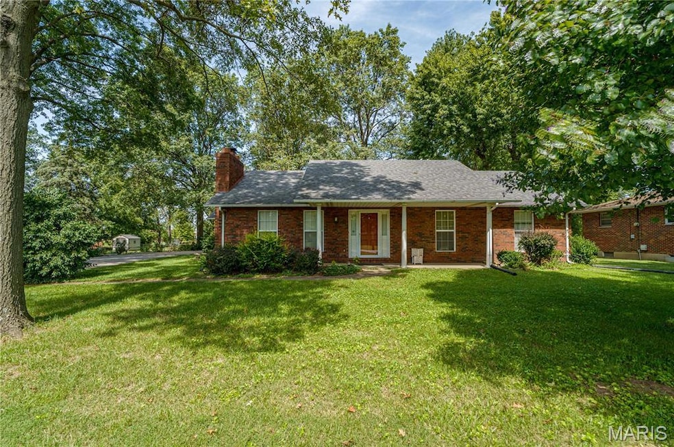 Ranch-style house featuring a front yard, a porch, a chimney, and brick siding