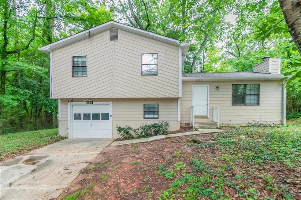 Split level home with a garage, a chimney, and concrete driveway