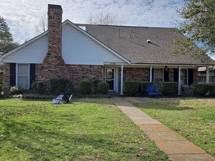 View of front of house featuring a chimney, brick 