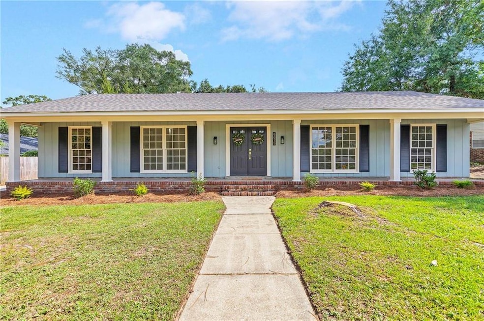 Ranch-style home with board and batten siding, roof with shingles, covered porch, and a front lawn