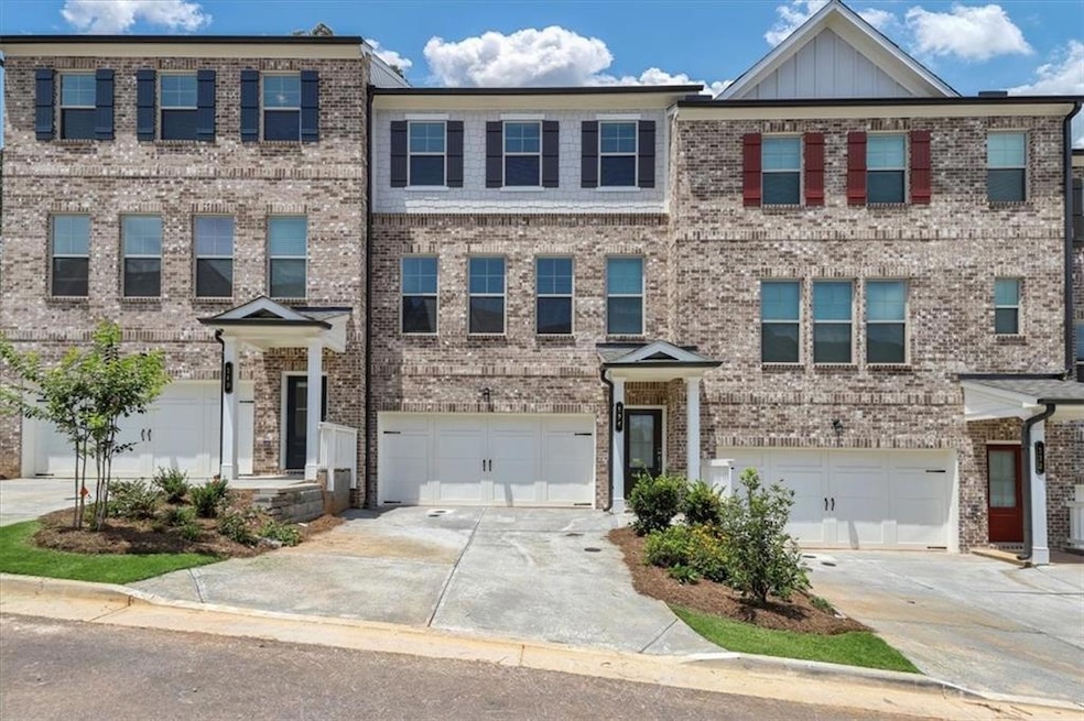 View of front of property with driveway, brick siding, an attached garage, and board and batten siding