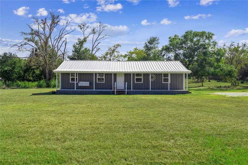 View of front of home with a front yard, a metal r