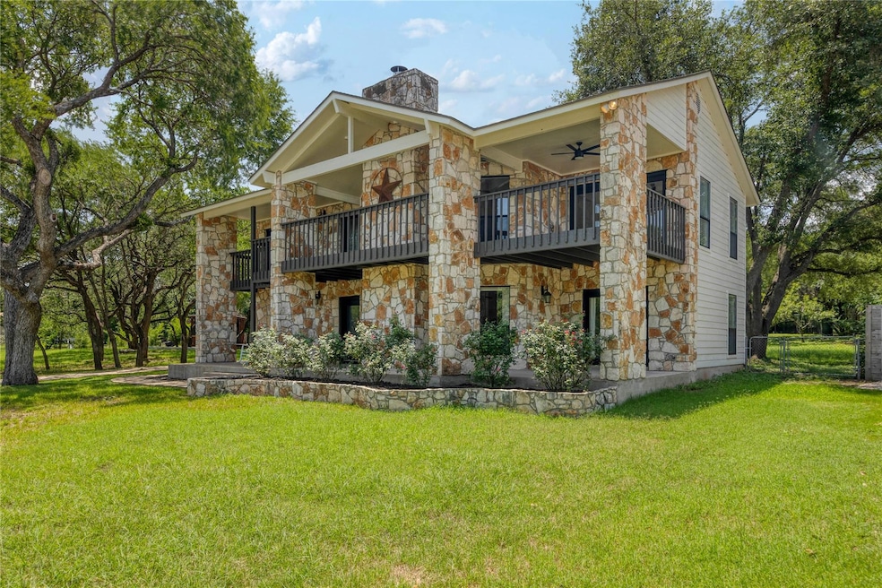 Back of house featuring stone siding, a balcony, 