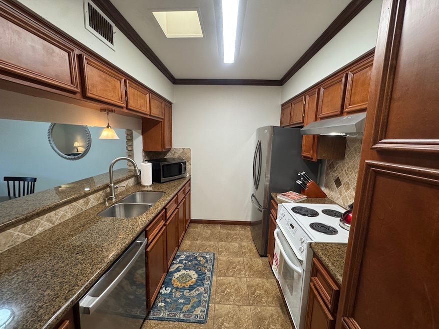 Galley kitchen with new refrigerator, vent hood, dishwasher, kitchen faucet and ceiling light fixture.