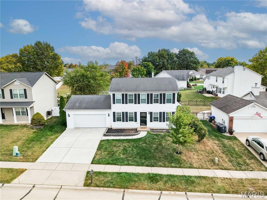 Colonial inspired home featuring a front lawn, concrete driveway, a garage, and a residential view