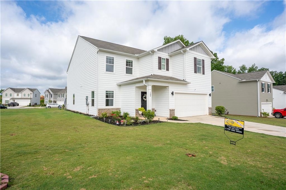 View of front facade with an attached garage, concrete driveway, a front yard, and board and batten siding
