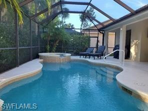 View of pool with a patio, glass enclosure, and an