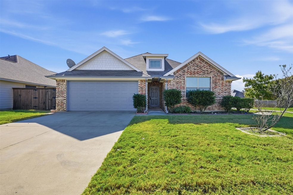 Traditional-style house with driveway, brick siding, roof with shingles, and a garage