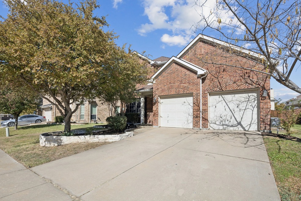 View of front of property with concrete driveway, brick siding, a front yard, and an attached garage