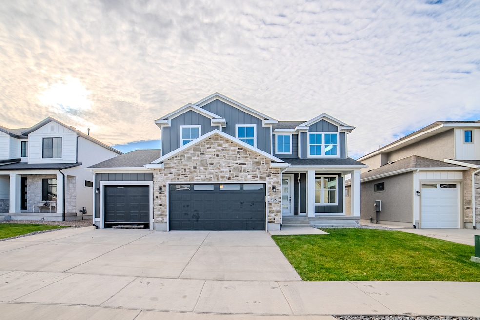 View of front facade featuring board and batten siding, concrete driveway, a garage, a front lawn, and stone siding