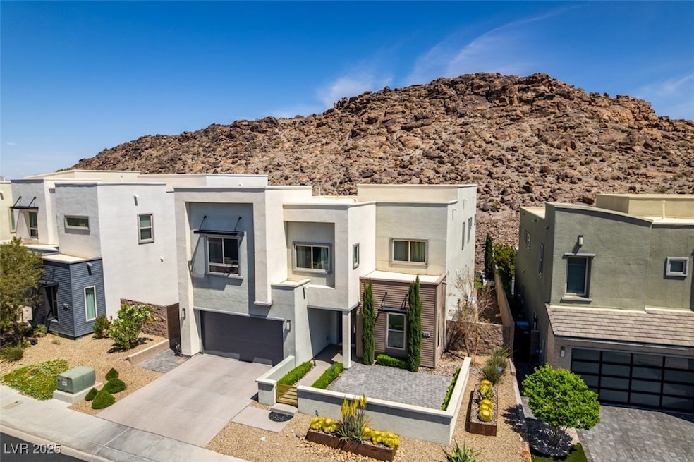 Modern home with driveway, stucco siding, an attached garage, and a mountain view