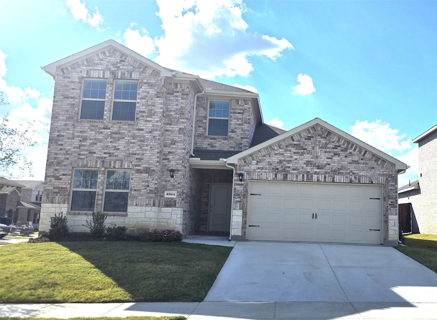 Traditional-style home with a garage, concrete driveway, a front lawn, and brick siding