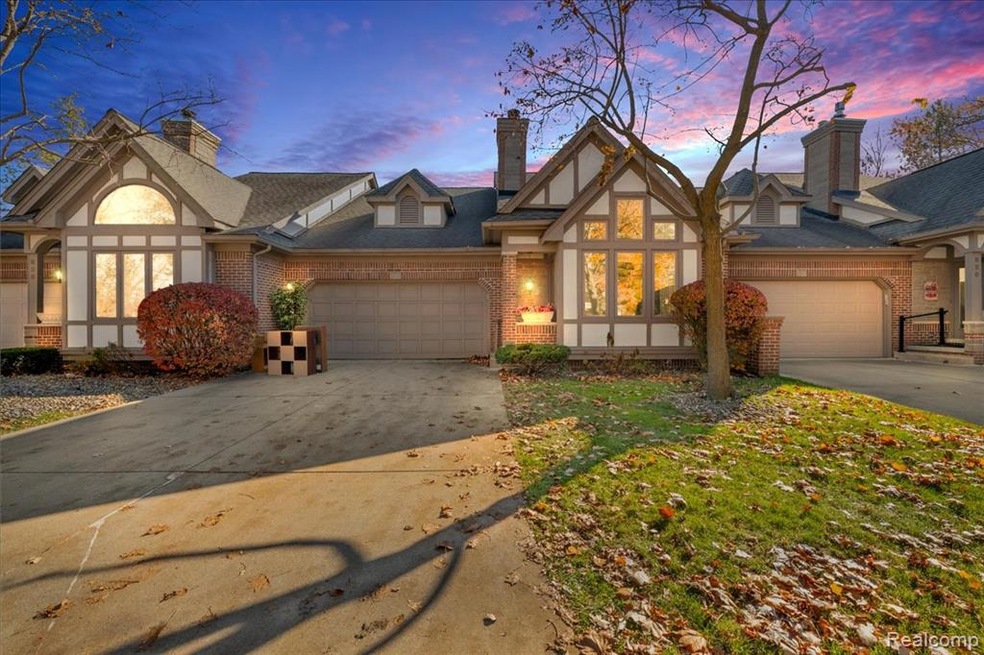 English style home featuring brick siding, concrete driveway, a chimney, and an attached garage