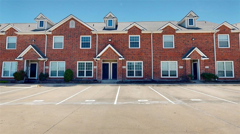View of property with uncovered parking and brick