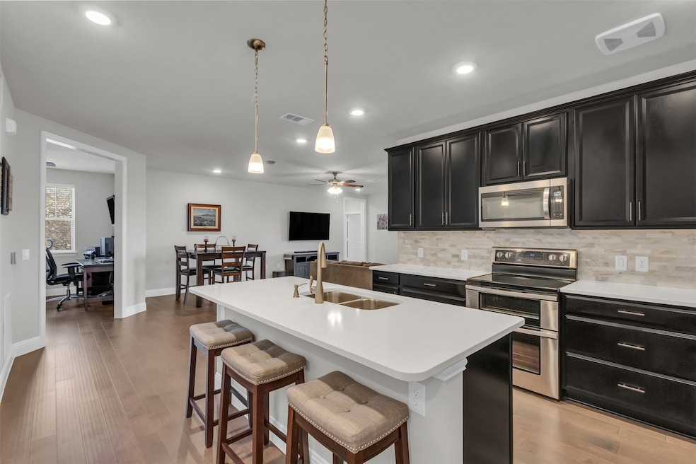 Kitchen featuring sink, stainless steel appliances, an island with sink, and a kitchen bar