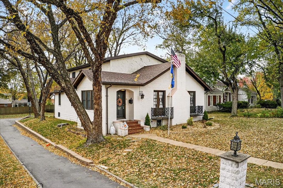 View of front of home featuring brick siding, a chimney, and roof with shingles