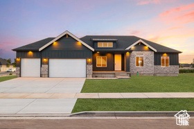 View of front of home with stone siding, a porch, a lawn, concrete driveway, and a garage