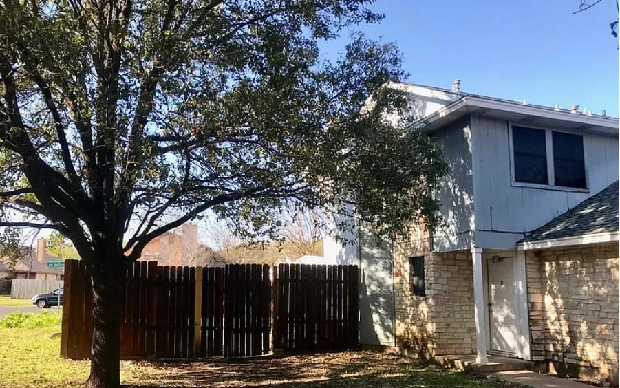 View of home's exterior featuring fence, brick si