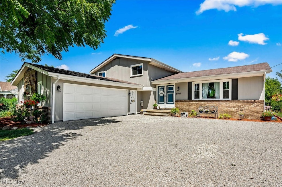 Split level home with brick siding, gravel driveway, and an attached garage