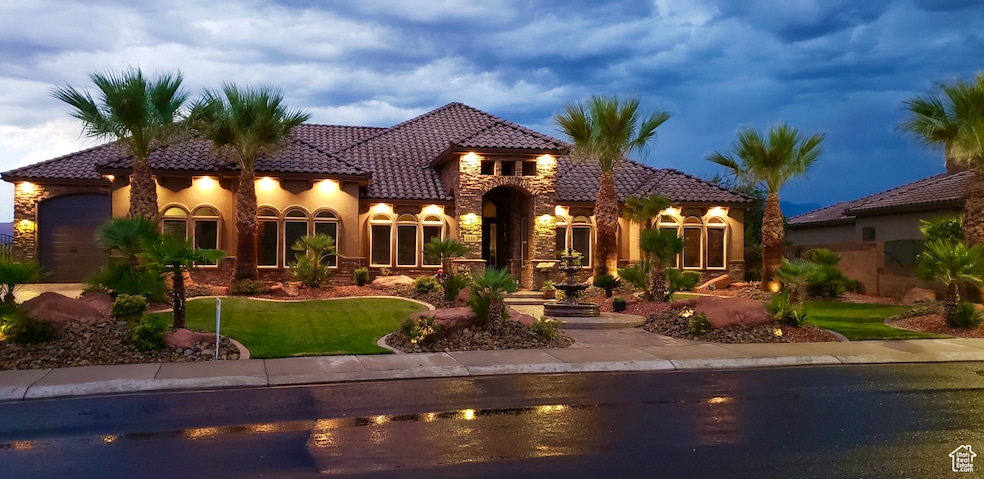 View of front of house with a lawn, stucco siding, an attached garage, and a tiled roof