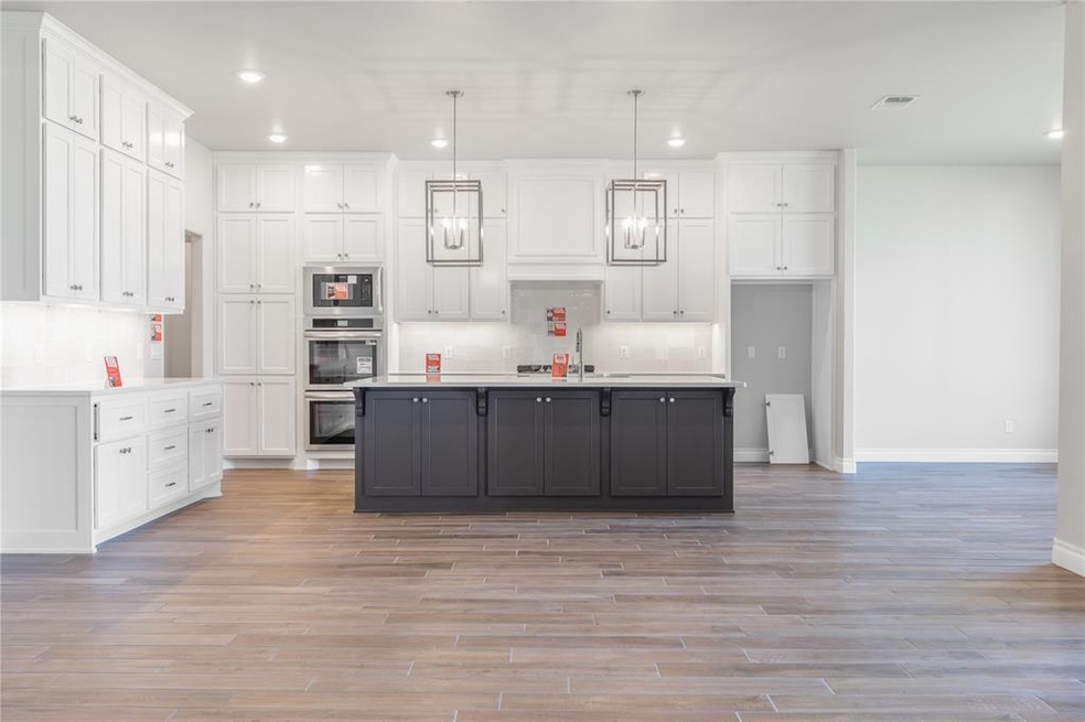 Kitchen with white cabinetry, decorative light fixtures, decorative backsplash, recessed lighting, and a kitchen island with sink