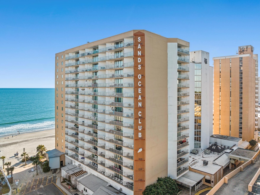 View of apartment building / complex featuring view of water and beach