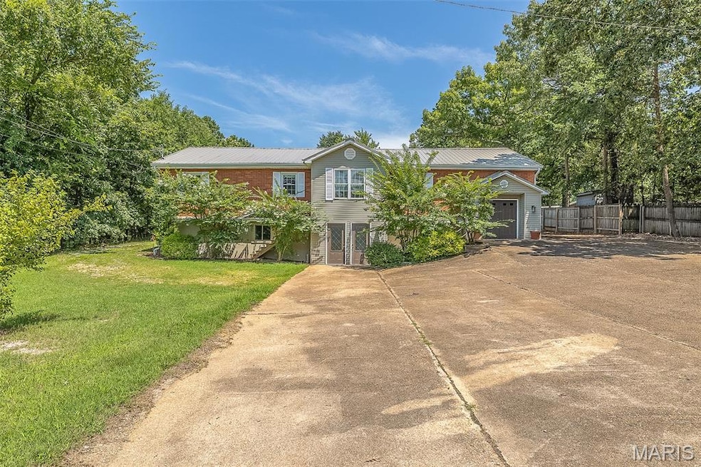 View of front facade with driveway and a metal roof