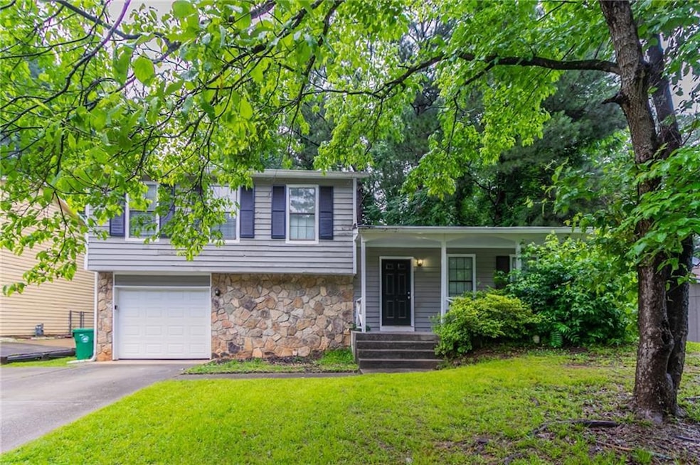 Split level home featuring stone siding, a front lawn, a garage, and a porch