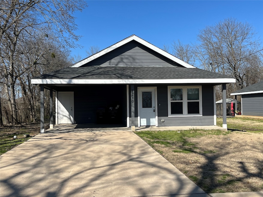View of front of property with covered porch, roof with shingles, concrete driveway, and an attached carport