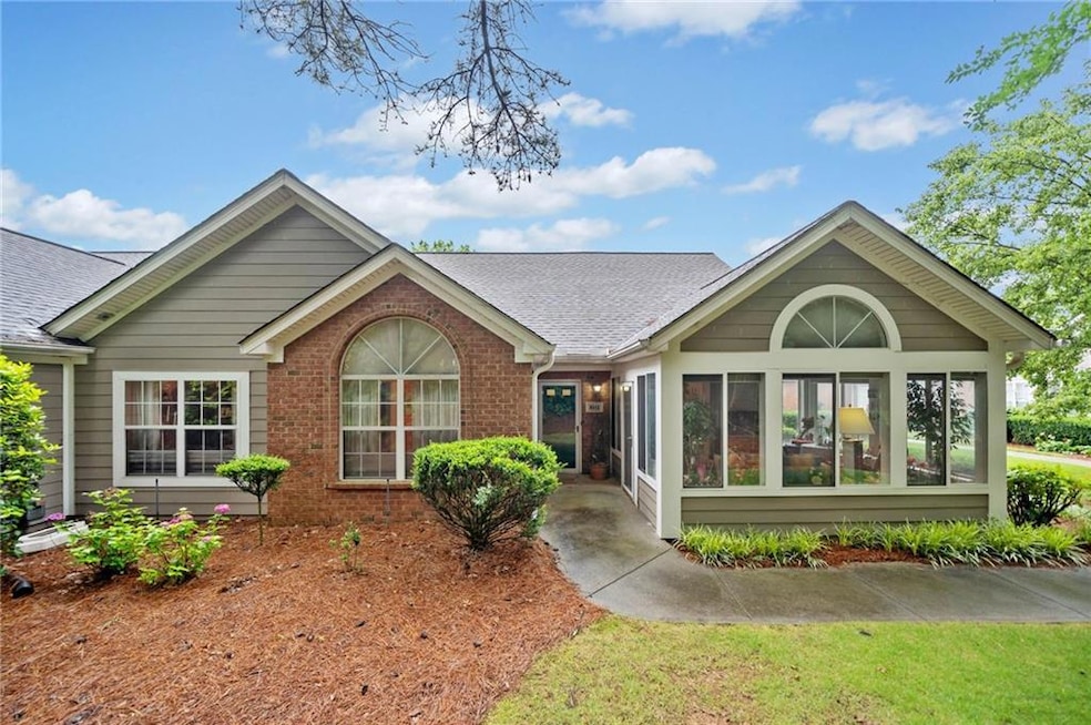 Back of house with a shingled roof, a sunroom, and brick siding