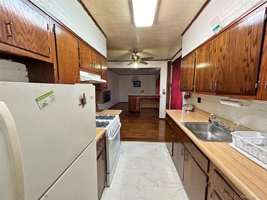 Kitchen with white appliances, under cabinet range hood, light countertops, light marble finish floors, and ceiling fan