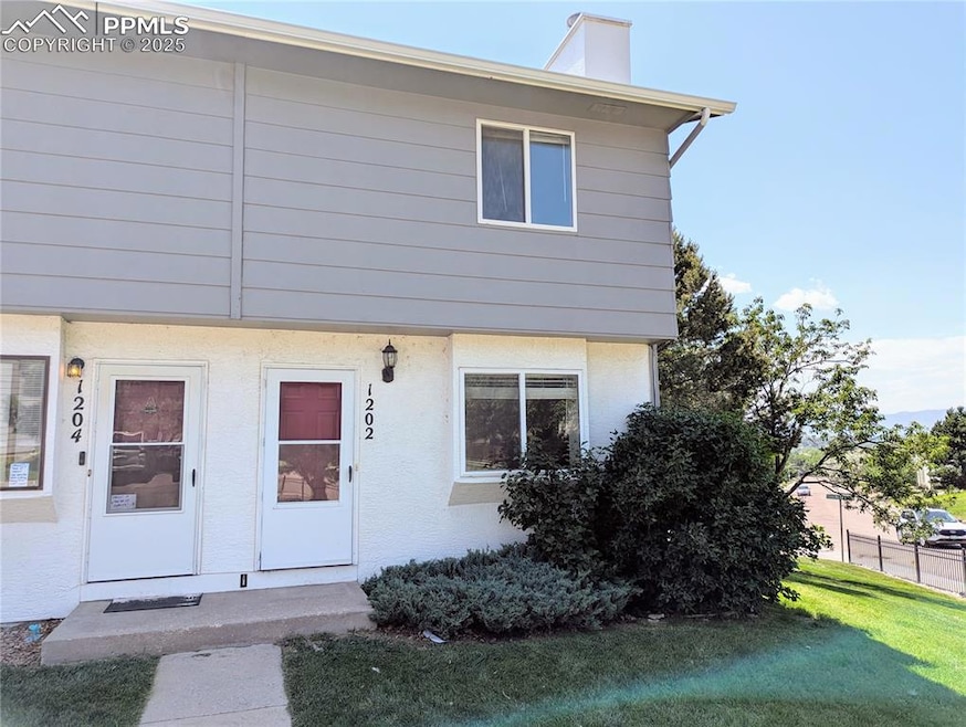 View of front of property featuring a front lawn, a chimney, and stucco siding