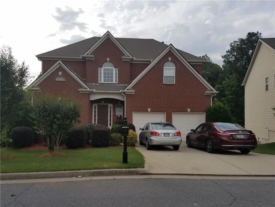 Traditional home with brick siding, a garage, driveway, and a front yard