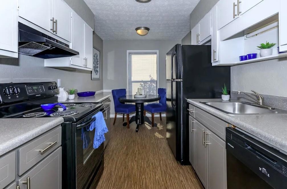 Kitchen with black appliances, wood-type flooring,