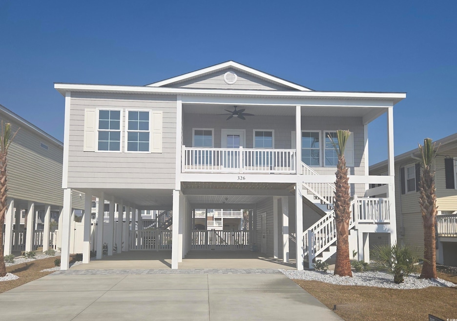 Raised beach house with driveway, covered porch, ceiling fan, stairs, and a carport
