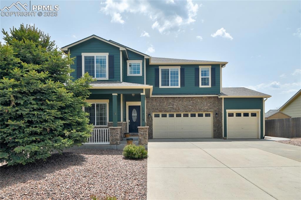 View of front of home featuring covered porch, stone siding, long driveway, and a 3 car garage