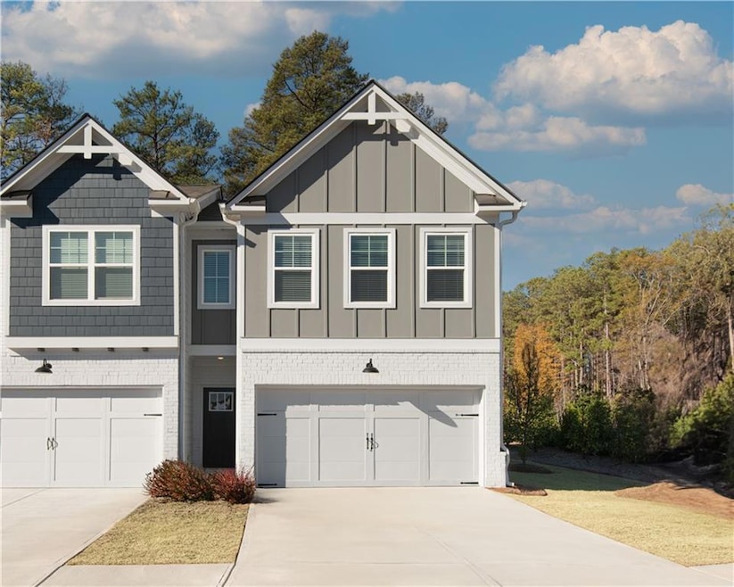 View of front of home with an attached garage, concrete driveway, board and batten siding, and brick siding