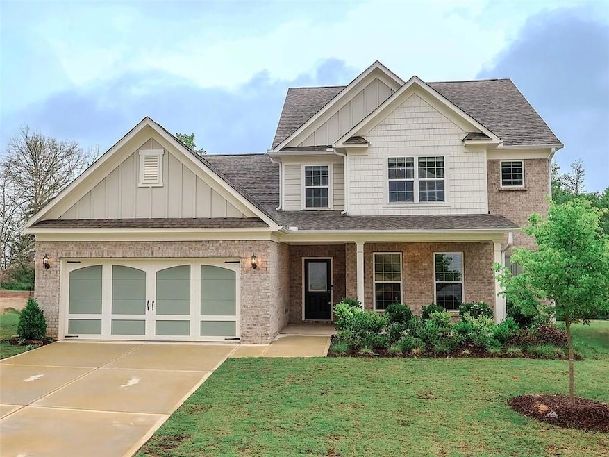 Craftsman-style house featuring covered porch, a shingled roof, a front yard, board and batten siding, and concrete driveway
