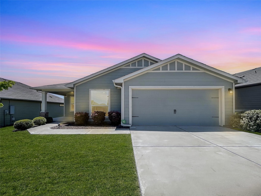 Ranch-style house with driveway, a lawn, and a ga