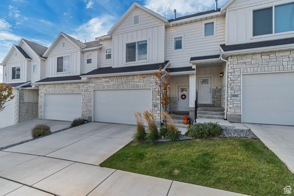 View of front of house featuring board and batten siding, stone siding, driveway, and a garage
