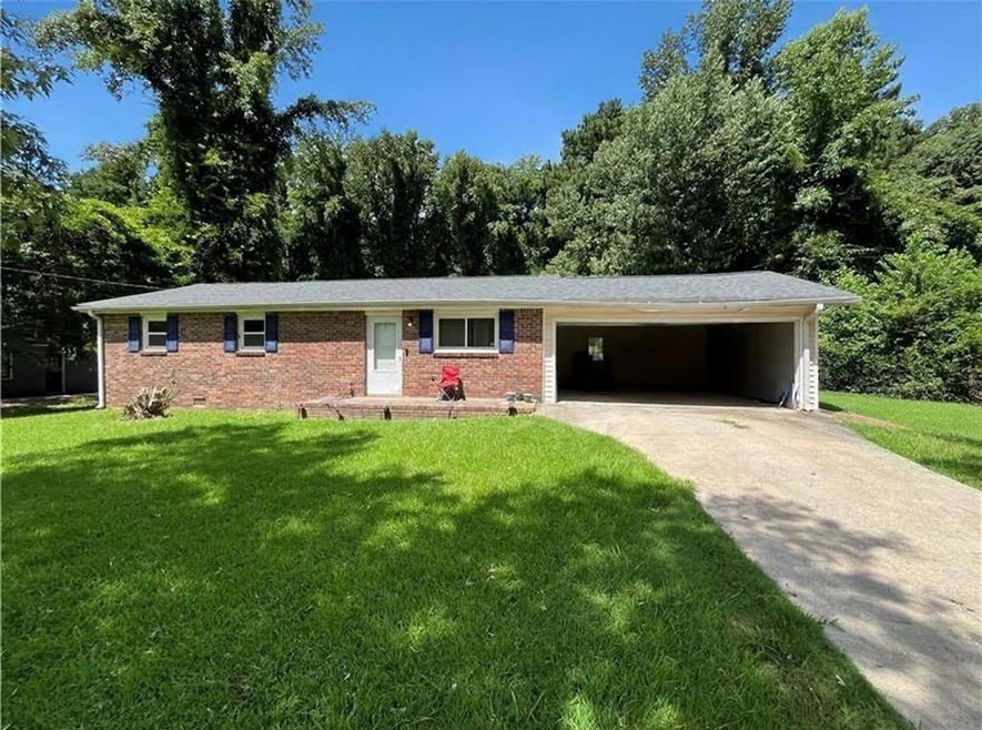 Single story home featuring driveway, a garage, brick siding, and a front lawn